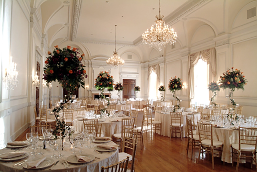 Eleganter, hell erleuchteter Ballsaal im Oheka Castle mit runden, festlich gedeckten Tischen und großen floralen Arrangements