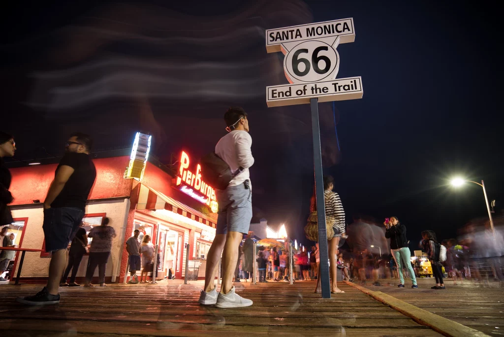 Menschenmenge bei Nacht am „End of the Trail“-Schild der Route 66 in Santa Monica