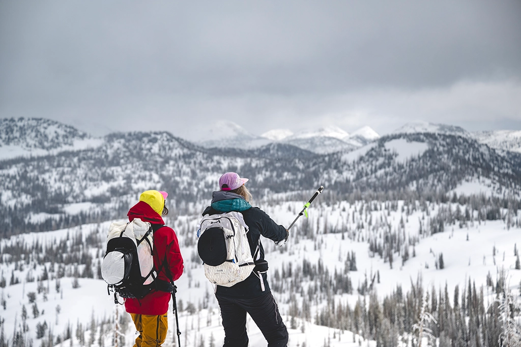 Zwei Skitourengeher mit Rucksäcken und Stöcken inmitten der verschneiten Uinta Mountains, Utah.