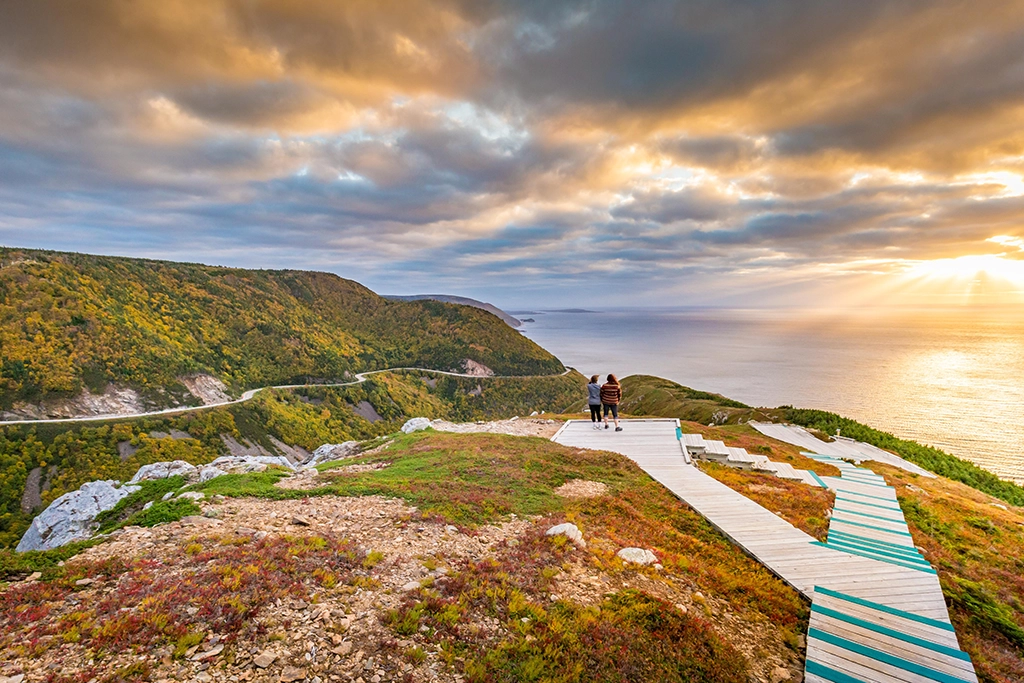 Wanderer auf dem Skyline Trail mit Blick auf die Steilküste und den Sonnenuntergang im Cape Breton Highlands National Park