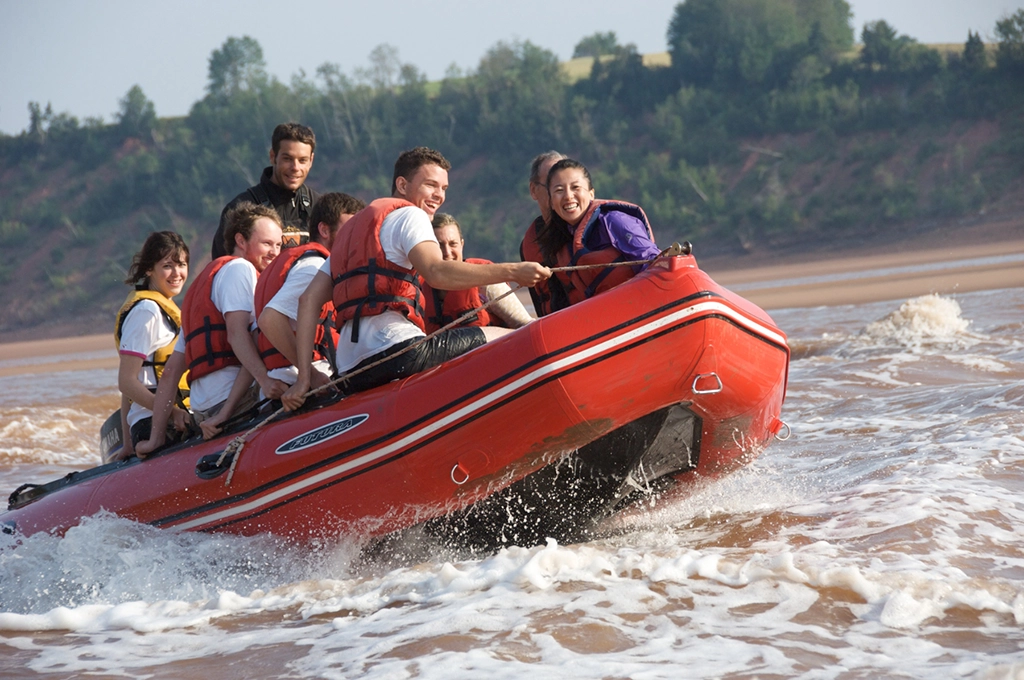 Gruppe junger Menschen beim Tidal Bore Rafting in einem Schlauchboot auf der Bay of Fundy
