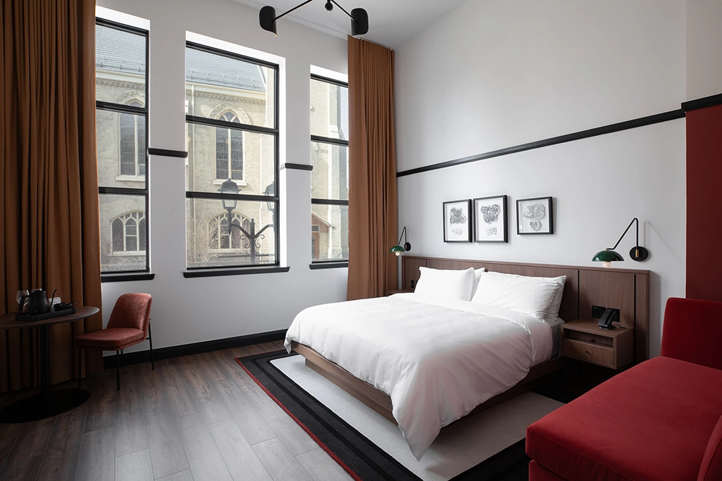 Modernes Deluxe-Kingsize-Zimmer mit Designmöbeln und hohen Fenstern im The Postmark Hotel.