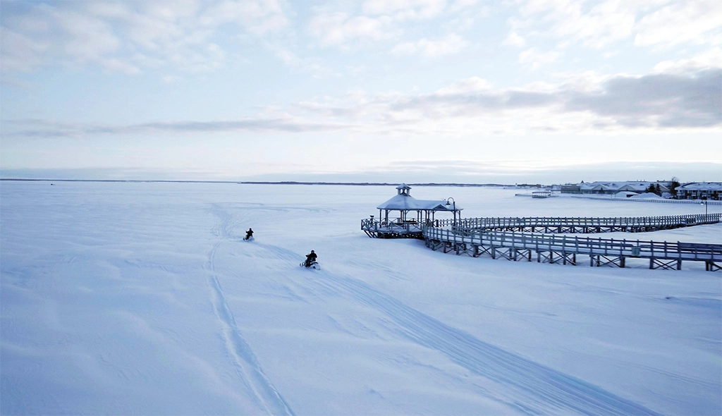 Zwei Schneemobile fahren über das verschneite Eis vor der Acadian Peninsula in New Brunswick, Kanada.