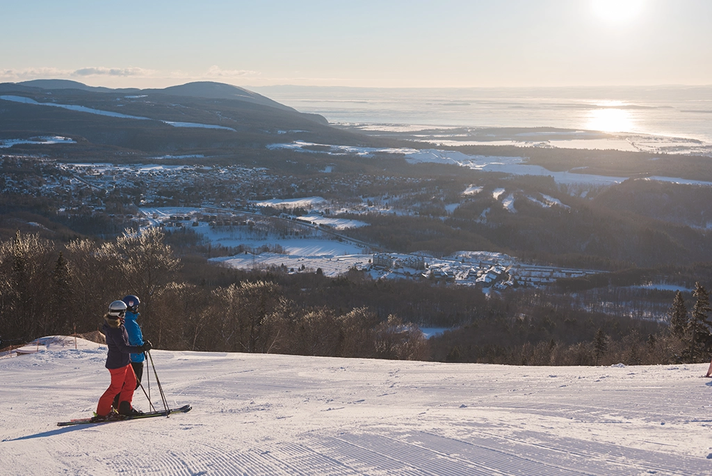 Skifahrer auf einer präparierten Abfahrt im Skigebiet Mont-Sainte-Anne mit Blick auf den Sankt-Lorenz-Strom