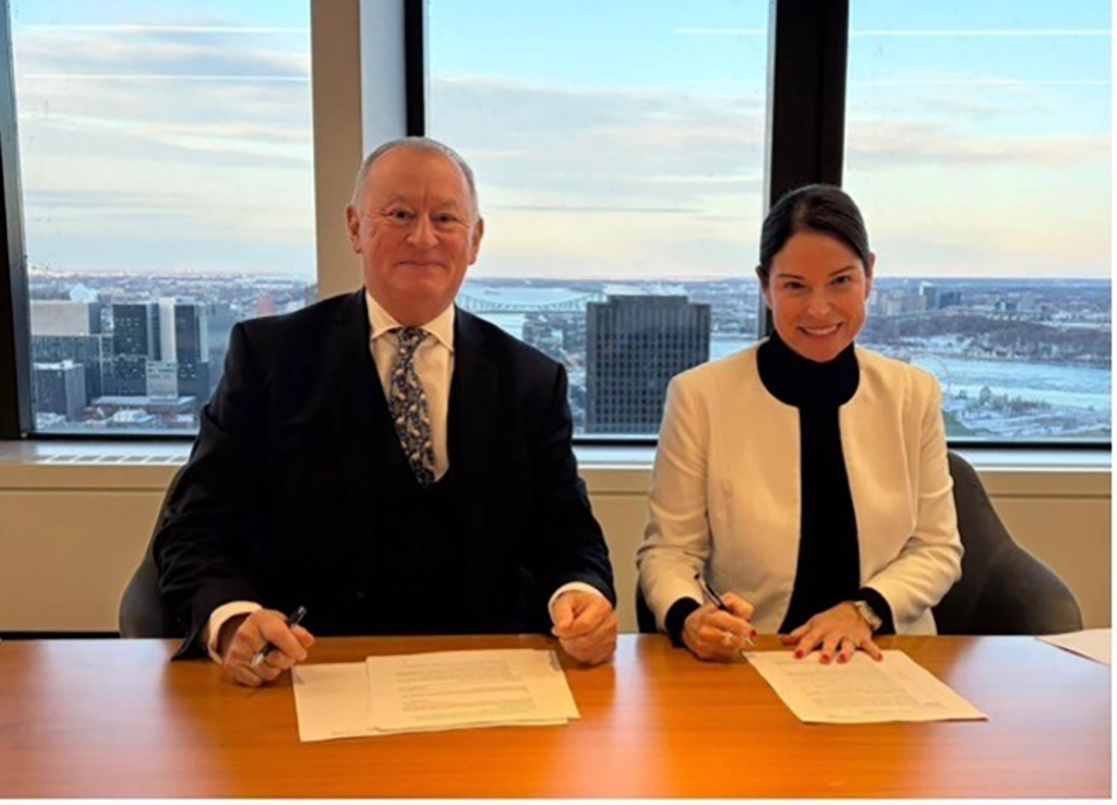Rémy Bourgeon und Carolyne Doyon sitzen an einem Tisch und unterzeichnen den Vertrag für Club Med Tremblant mit Blick über Montréal.