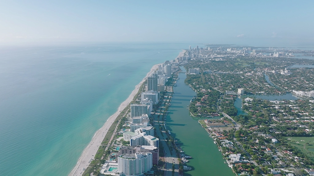 Luftaufnahme von Miami Beach mit Hochhäusern, Strand und parallel verlaufendem Kanal
