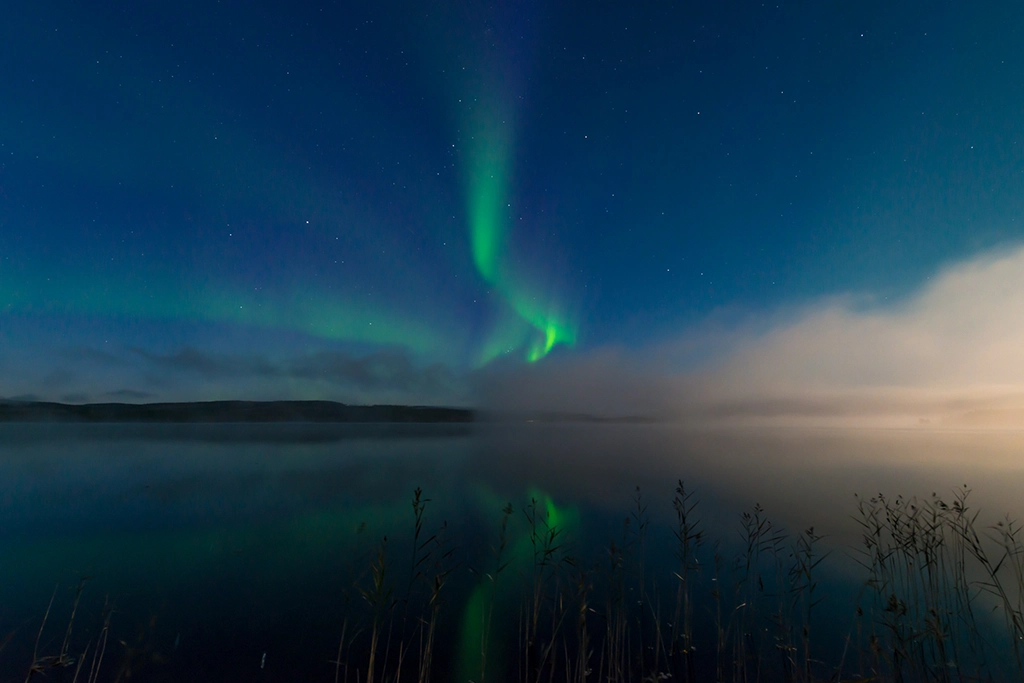 Nordlichter spiegeln sich in einem ruhigen Wintersee in Nordschweden.