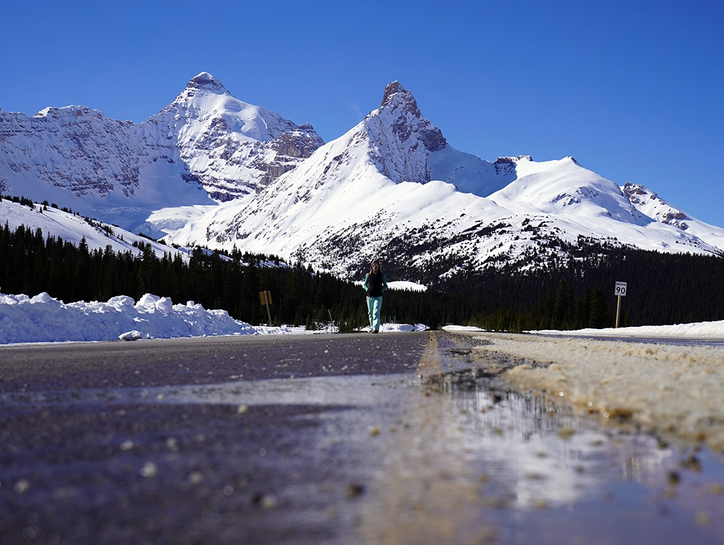 Winterliche Bergstraße mit Blick auf schneebedeckte Gipfel am Icefields Parkway in Alberta