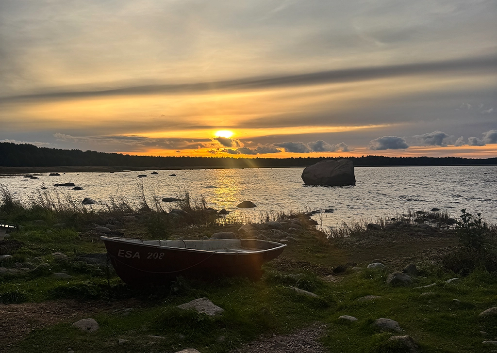 Sonnenuntergang an der Ostsee mit Fischerboot, Felsen und ruhigem Wasser im Herbst
