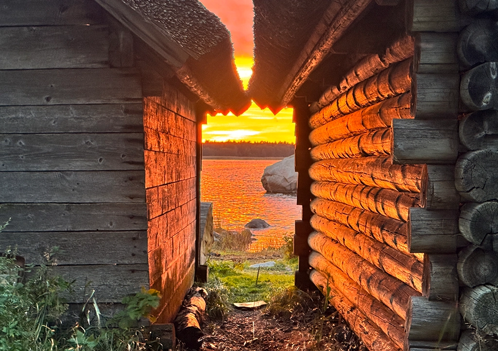 Sonnenuntergang über der Ostsee, gesehen durch den Durchgang zweier hölzerner Fischerhütten in Altja