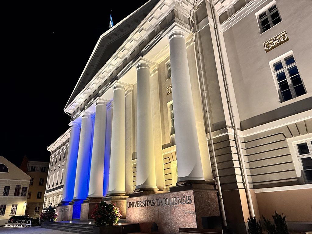 Beleuchtete Universität Tartu mit klassizistischer Säulenfassade bei Nacht