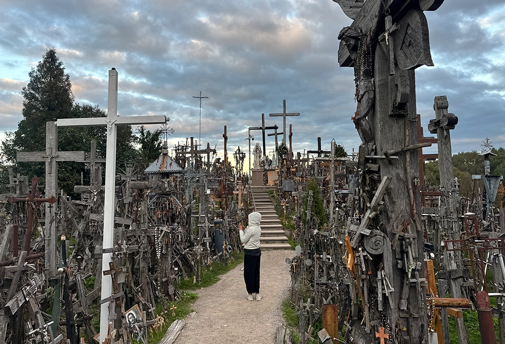 Besucher auf dem Hill of Crosses bei Šiauliai zwischen dicht stehenden Holzkreuzen