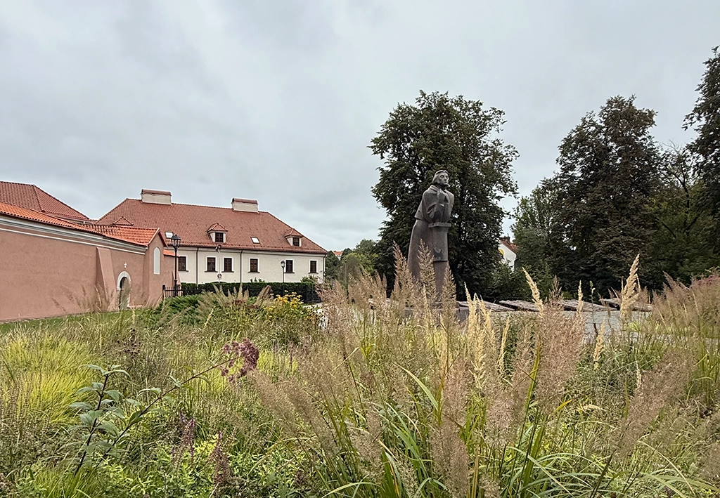 Statue in einer Grünanlage vor historischer Klosteranlage in Vilnius
