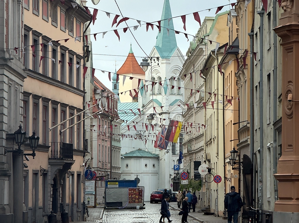 Schmale Altstadtgasse in Riga mit historischen Fassaden und Kirchturm