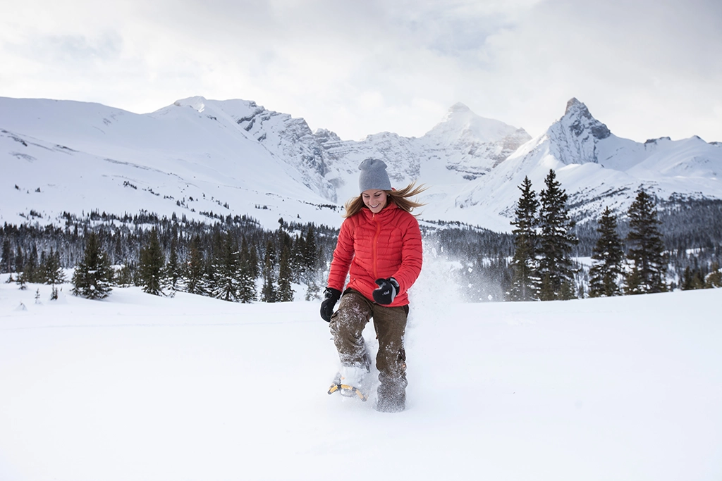 Frau stapft mit Schneeschuhen durch den tiefen Pulverschnee in den kanadischen Rockies