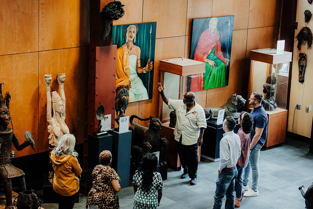 Besuchergruppe im Roots 101 African American Museum mit Kunstwerken und afrikanischer Skulpturensammlung