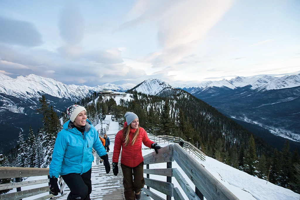 Zwei Frauen wandern im Winter auf dem Sulphur Mountain Boardwalk in Banff, Alberta