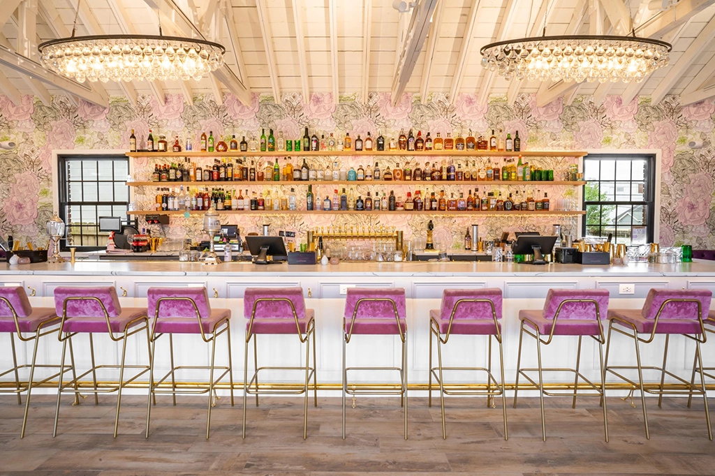 Barbereich des Restaurants Supperland mit gepolsterten Barhockern, Kronleuchtern und umfangreicher Spirituosenauswahl