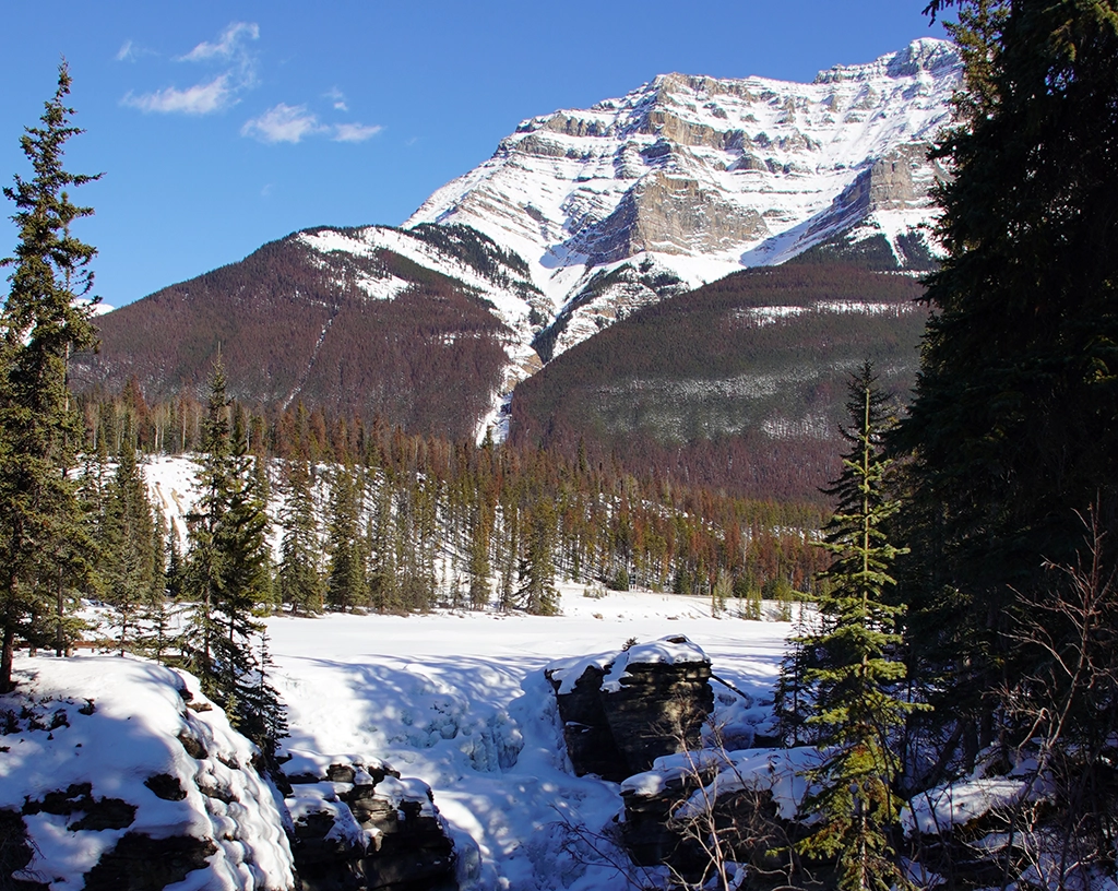 Verschneite Berglandschaft mit gefrorenem Wasserfall in den kanadischen Rockies