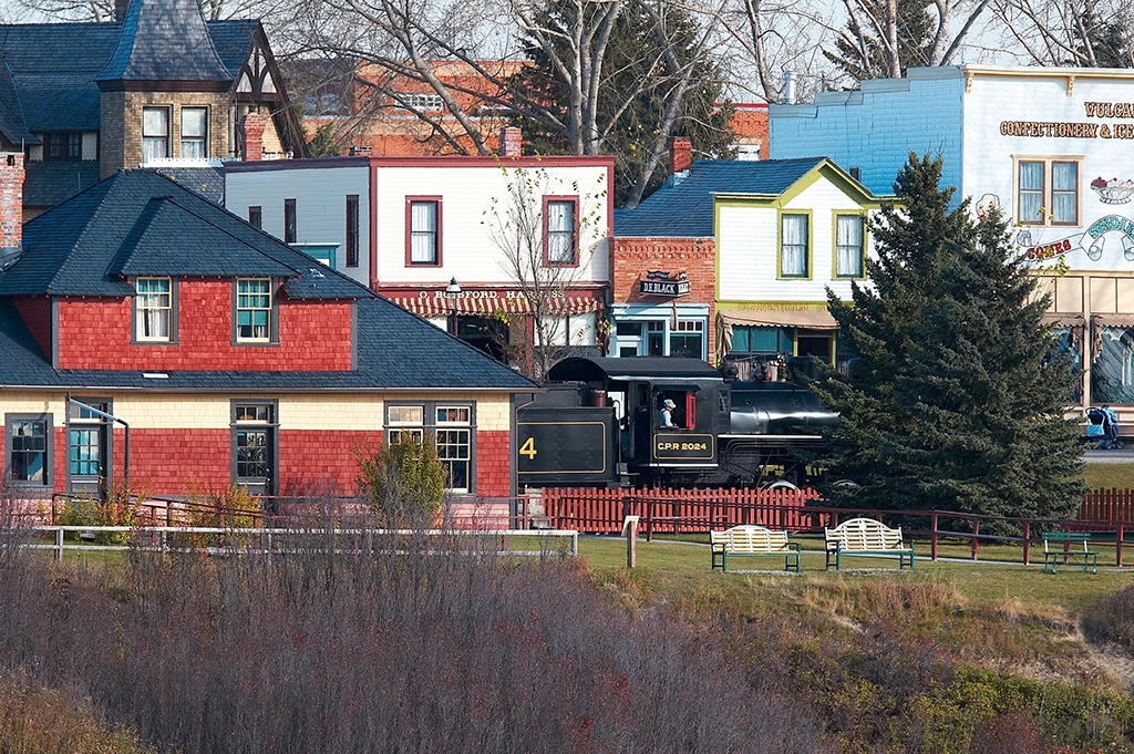 Historische Dampflok fährt durch Heritage Park Historical Village in Calgary mit originalgetreuen Gebäuden aus dem frühen 20. Jahrhundert