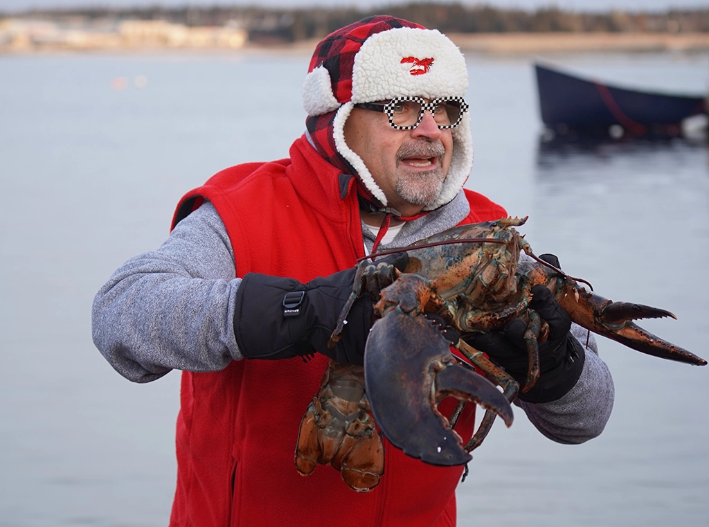 Mann mit Wintermütze und Hummer am Hafen in Nova Scotia