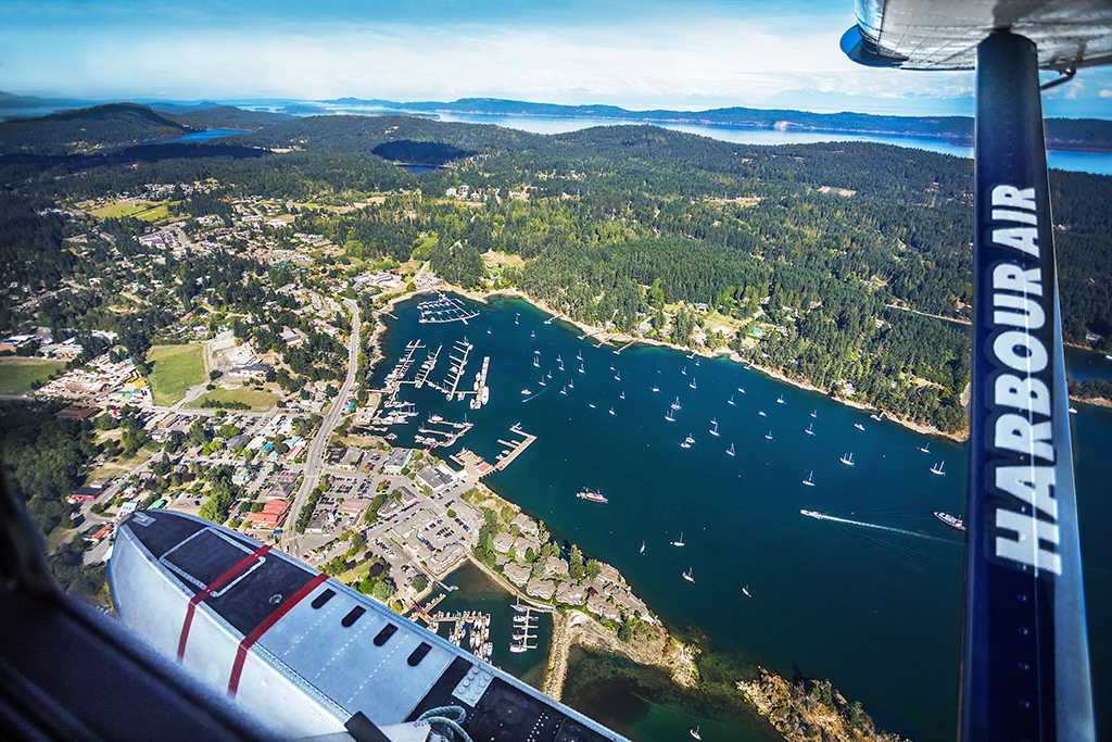 Luftaufnahme von Ganges Harbour auf Salt Spring Island mit Segelbooten und bewaldeter Küste.