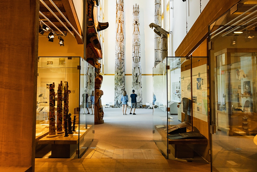 Innenansicht des Haida Gwaii Museums mit geschnitzten Totempfählen und Ausstellungsraum.