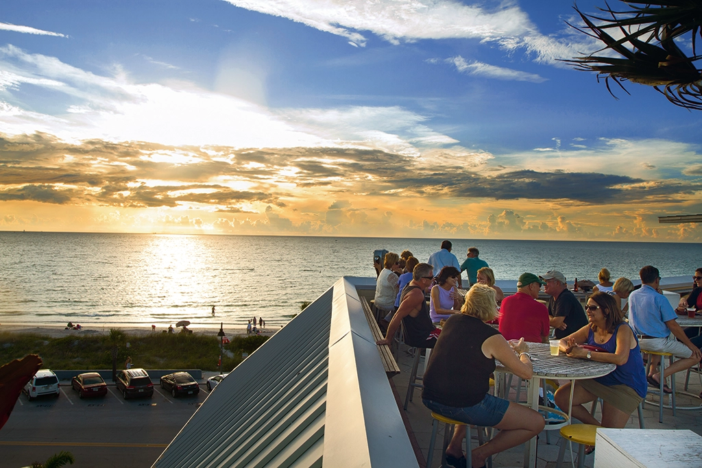 Gäste genießen Drinks bei Sonnenuntergang auf der Rooftop-Bar des Hurricane Seafood Restaurant mit Blick auf den Golf von Mexiko.