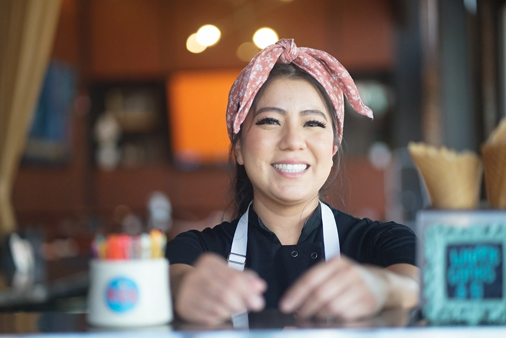 Lächelnde Konditorin mit rosa Haarband hinter der Theke des HUB Restaurant & Creamery in Tucson
