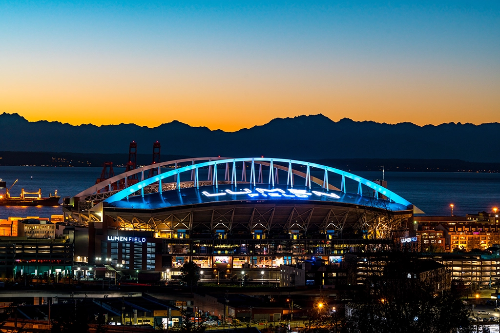 Lumen Field in Seattle bei Sonnenuntergang mit beleuchtetem Stadiondach.