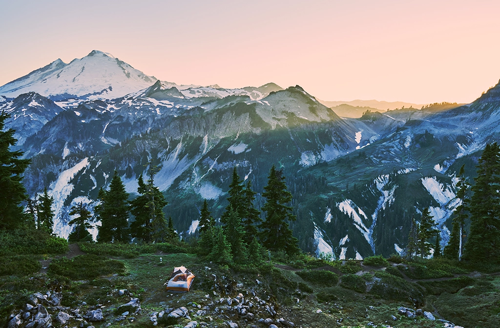 Zelt mit Blick auf Mount Baker und alpine Berglandschaft im Sonnenuntergang.