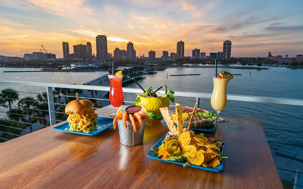 Menschen genießen Essen und Getränke bei Sonnenuntergang auf der Rooftop-Terrasse des Teak in St. Pete.