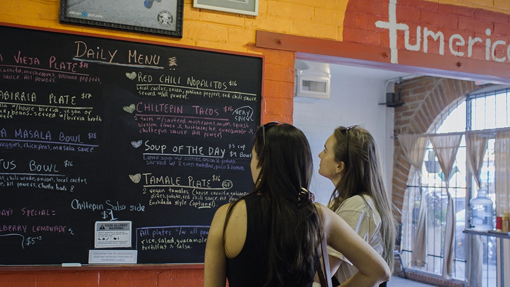 Zwei Frauen lesen die Menütafel im vegetarischen Restaurant Tumerico in Tucson.