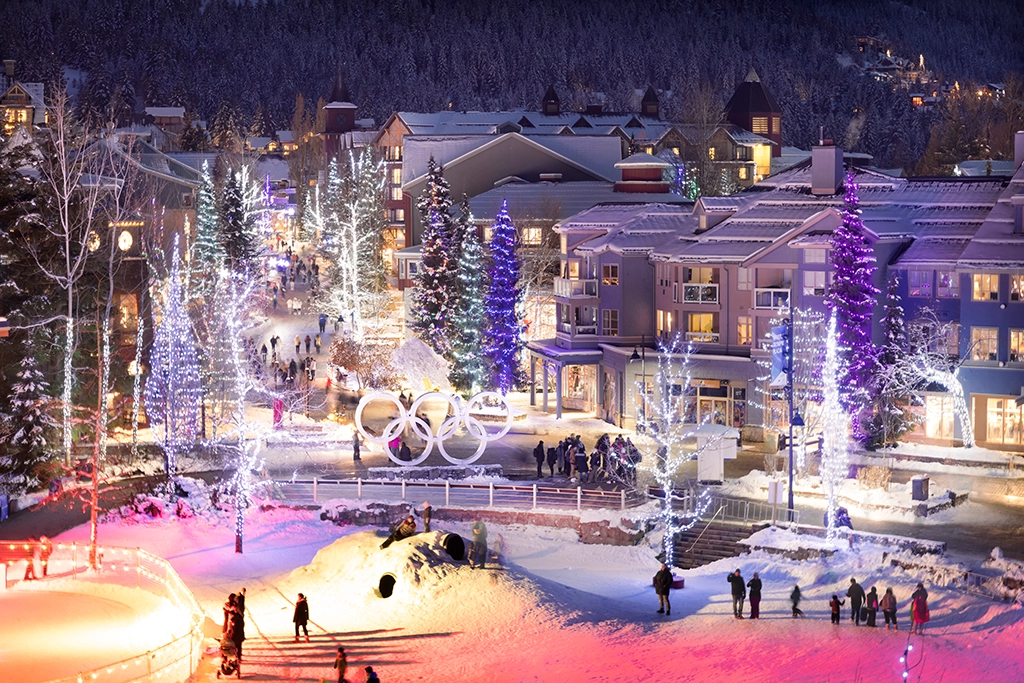 Whistler Olympic Plaza im Winter mit beleuchteten Bäumen und olympischen Ringen.