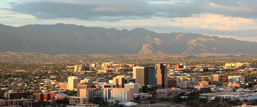 Blick über die Skyline von Tucson, Arizona, bei Sonnenuntergang mit Bergkulisse.