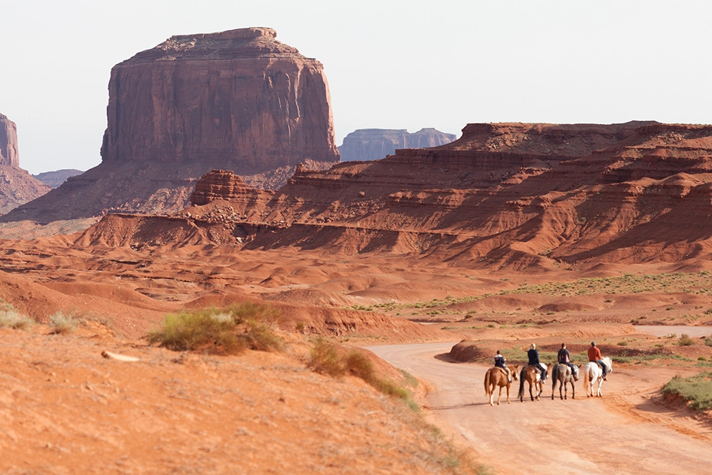 Reiter im Monument Valley Navajo Tribal Park vor roten Sandsteinformationen in Arizona.