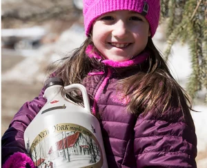 Kind hält eine Flasche Ahornsirup beim Maple Weekend in New York.