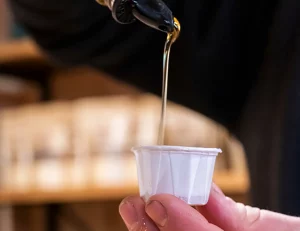 Frischer Ahornsirup wird in einen kleinen Becher gefüllt.