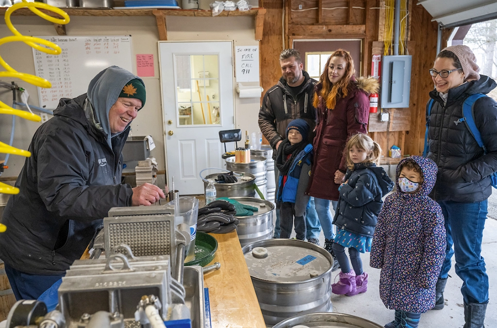 Besucherfamilie bei einer Führung zur Ahornsirup-Produktion in New York.