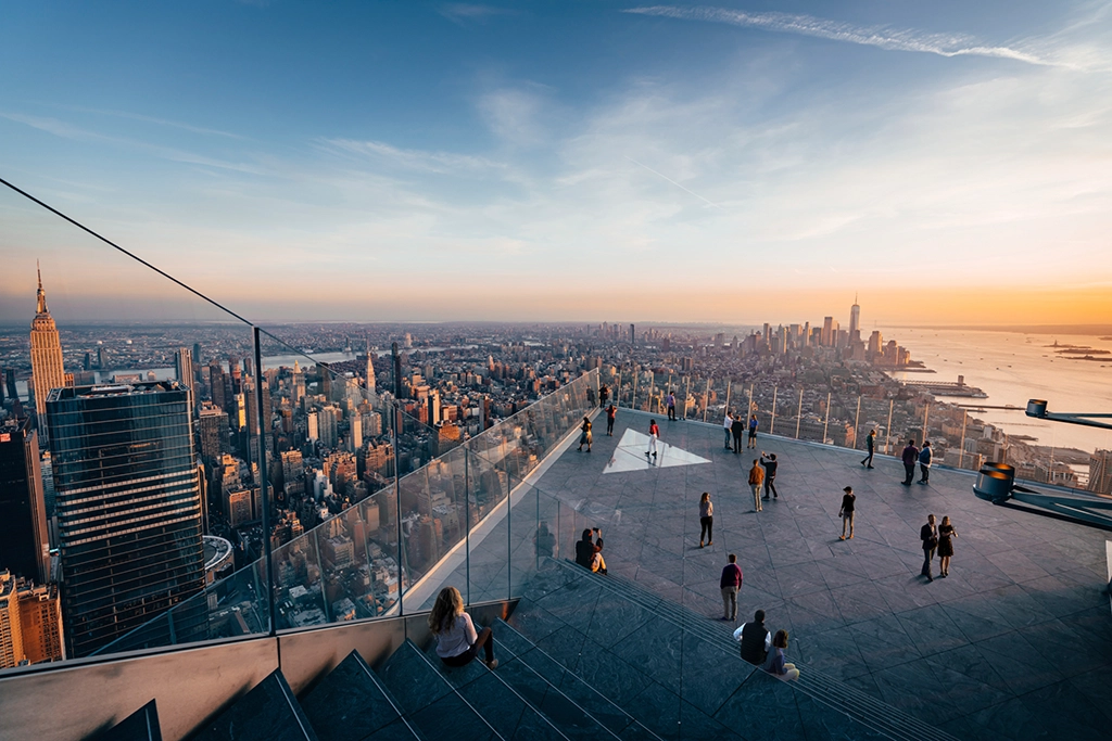 Aussichtsplattform mit Besuchern und Blick auf Manhattan bei Sonnenuntergang