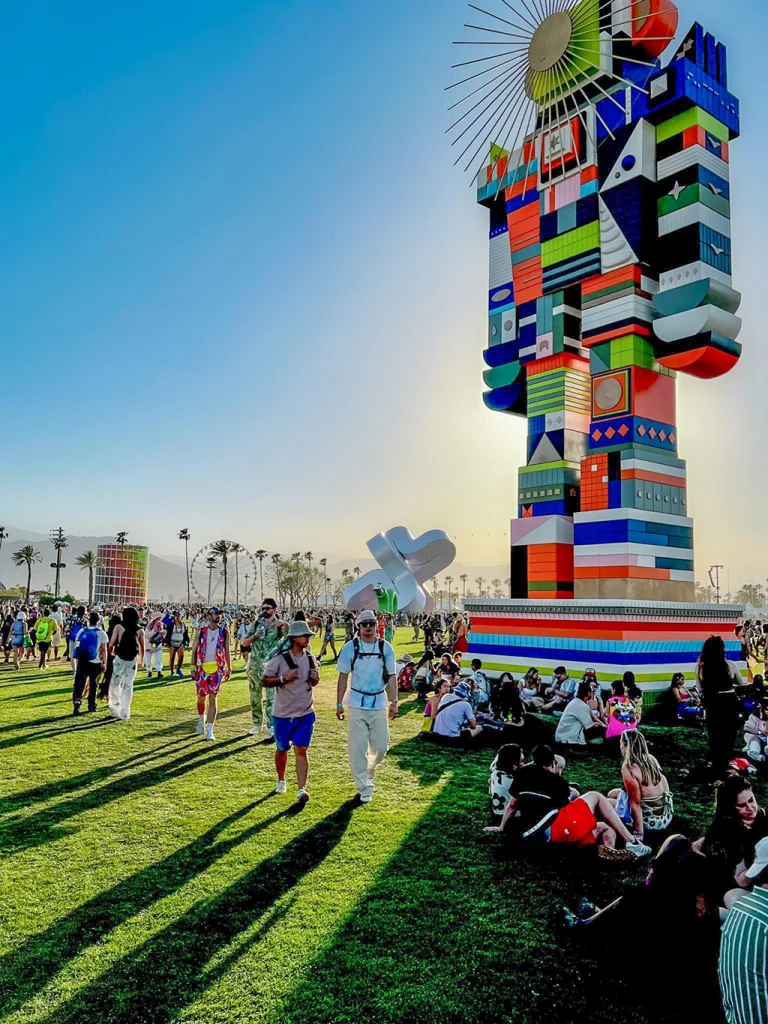 Besucher auf Festivalgelände mit großer Kunstinstallation beim Coachella Festival