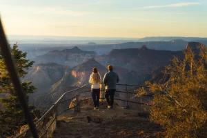 Paar betrachtet den Grand Canyon bei Sonnenaufgang am North Rim in Arizona.