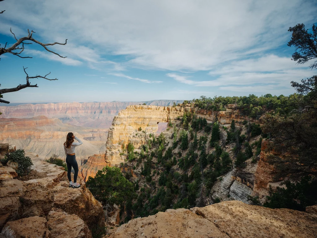 Besucherin blickt am North Rim des Grand Canyon auf Angels Window und die Canyonlandschaft in Arizona.