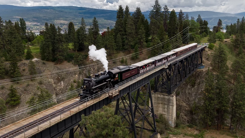 Historischer Dampfzug überquert eine hohe Eisenbahnbrücke in Summerland
