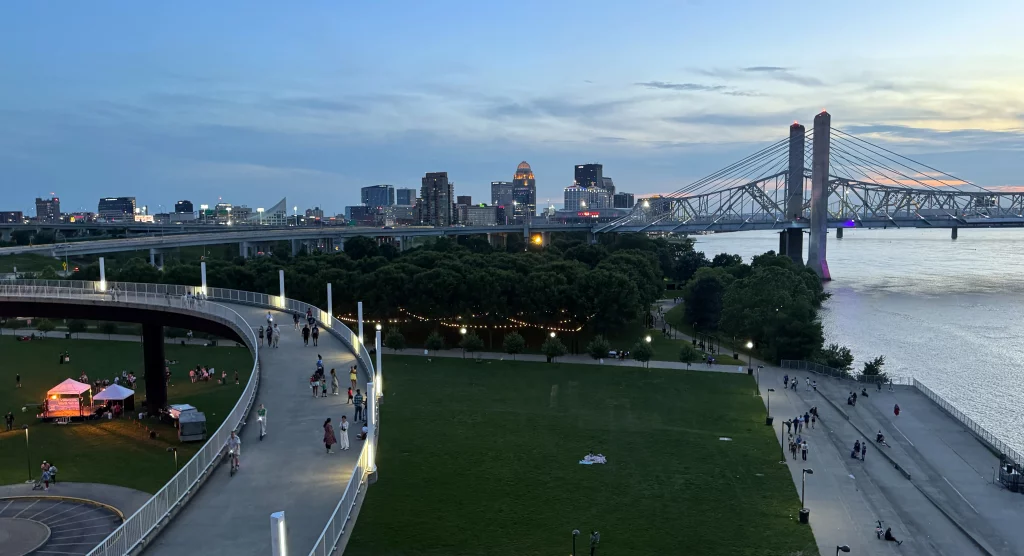 Blick von der Big Four Pedestrian Bridge auf den Big Four Lawn und den Waterfront Park in Louisville bei Sonnenuntergang mit Skyline und Ohio River.