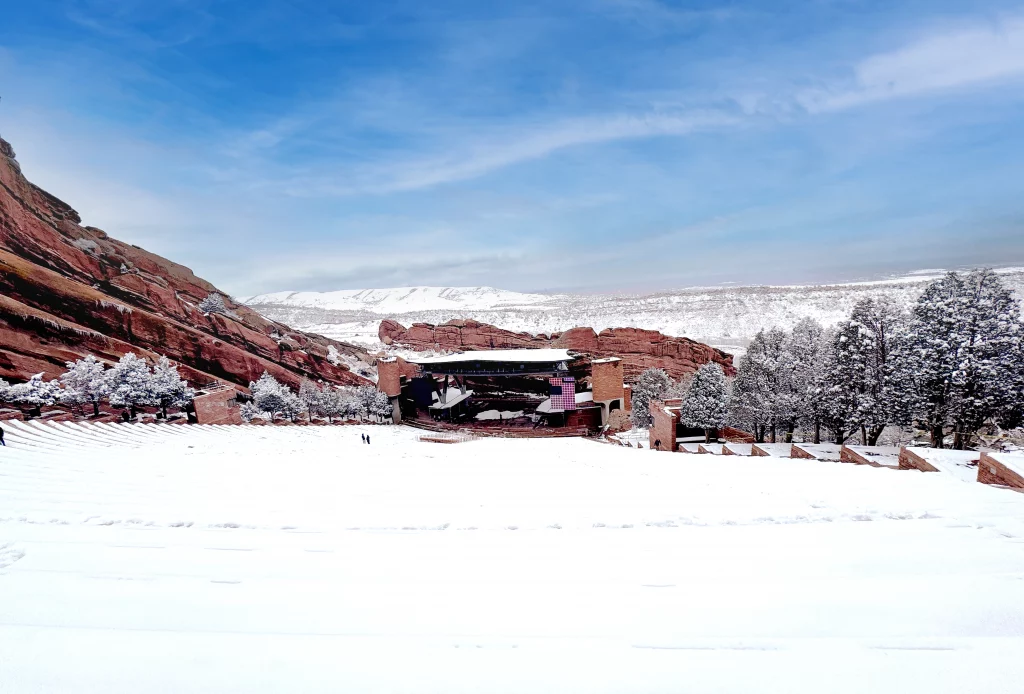 Verschneites Red Rocks Amphitheatre mit Bühne und roten Felsformationen in Colorado.