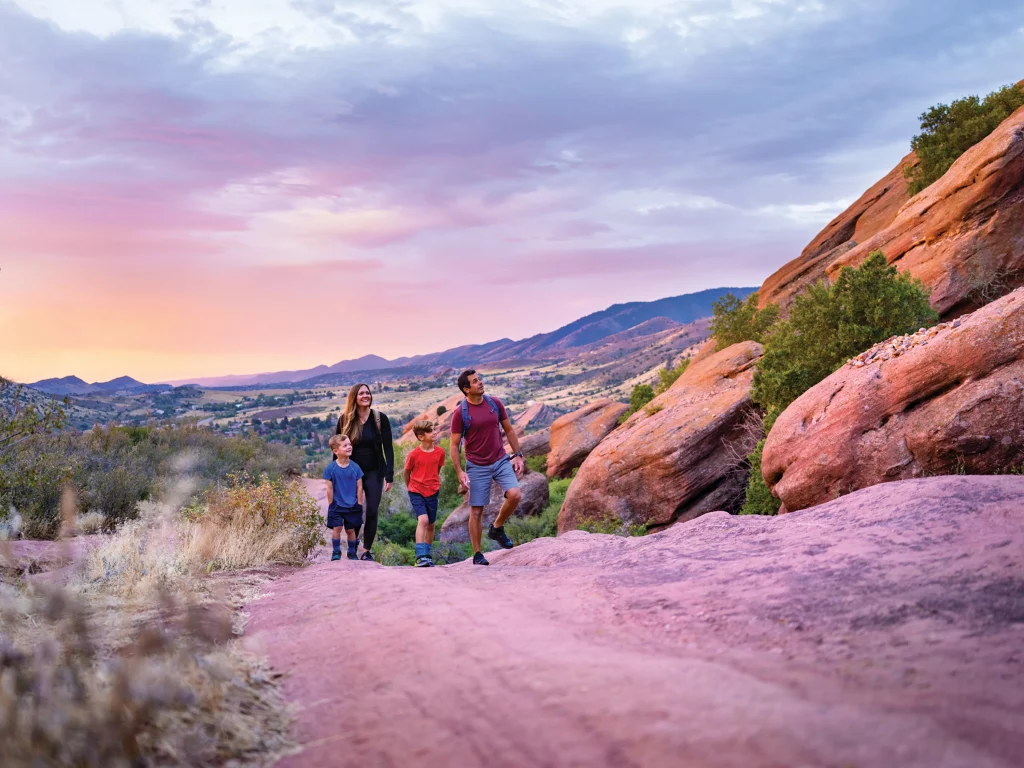 Familie wandert zwischen roten Felsformationen im Red Rocks Park bei Denver, Colorado.