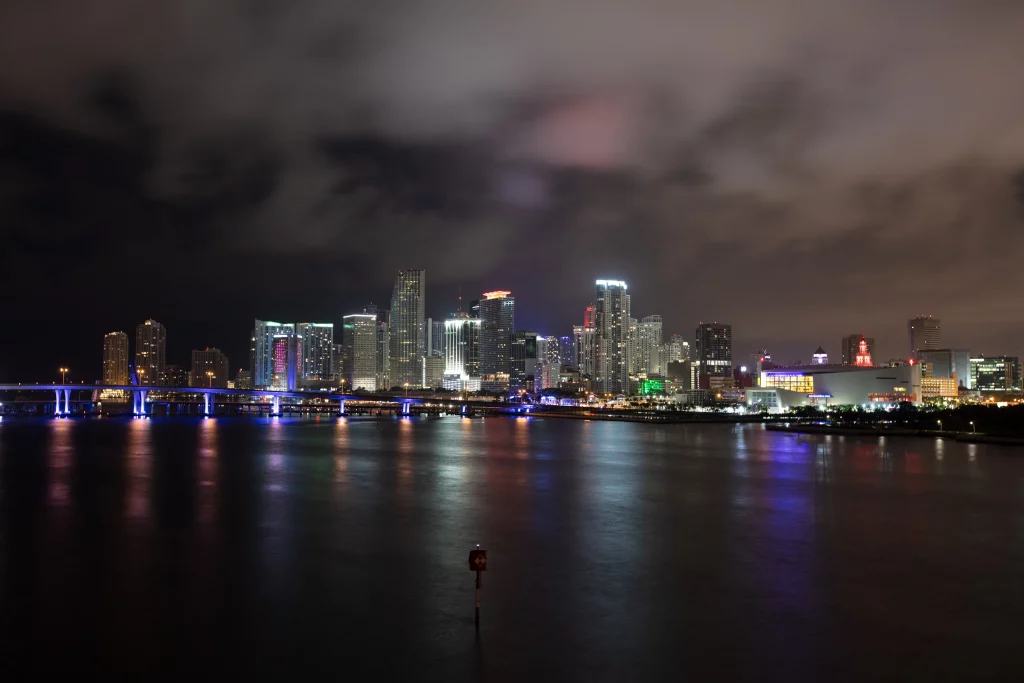 Beleuchtete Skyline von Downtown Miami bei Nacht mit Spiegelungen in der Biscayne Bay.