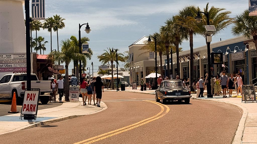 Straßenszene mit Palmen, Geschäften und Oldtimer nahe den Sponge Docks in Tarpon Springs, Florida.