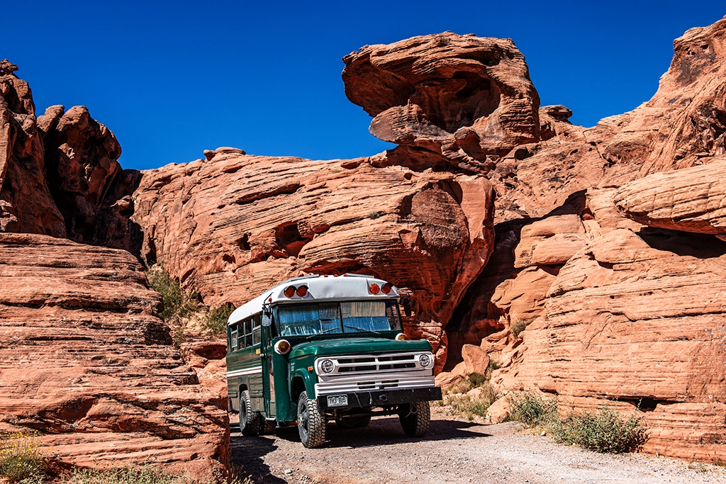 Alter grüner Schulbus zwischen roten Sandsteinfelsen im Valley of Fire State Park.